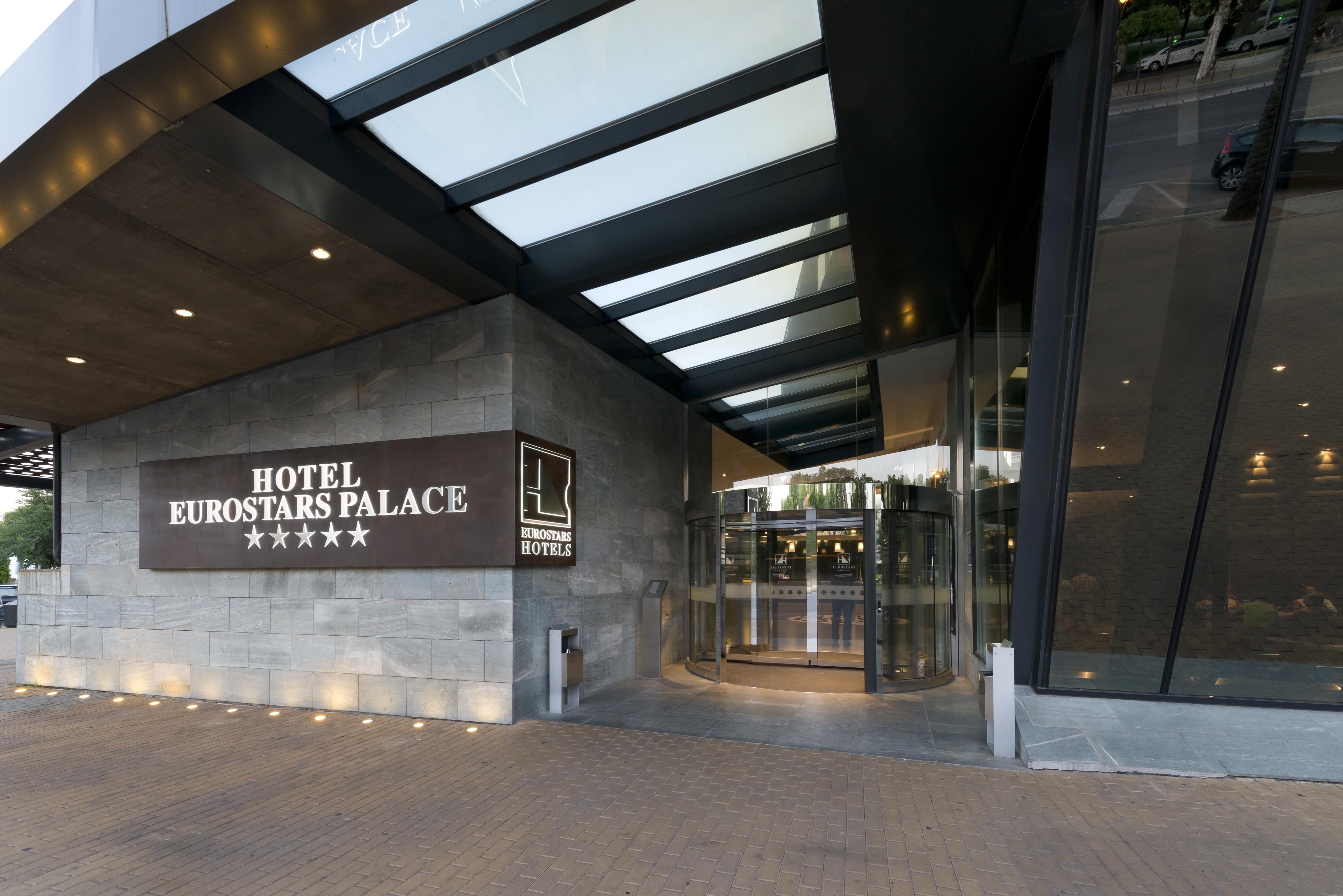 Eurostars Palace Kordoba Bagian luar foto The photo shows the entrance of the Eurostars Palace Hotel, which features a modern design. The entrance is characterized by a glass revolving door and a prominent sign that displays the hotel's name and five-star rating. The exterior has a combinati