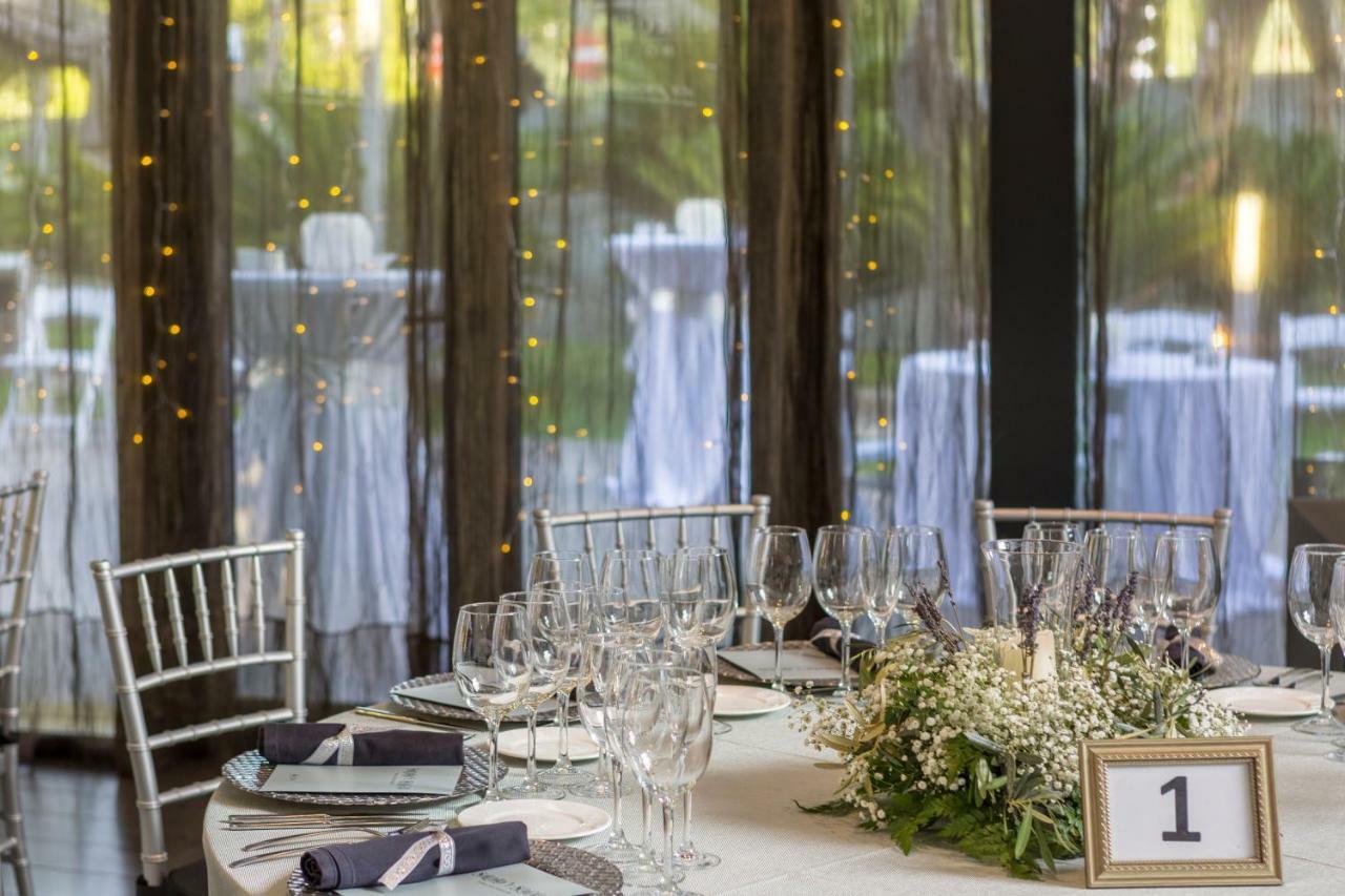 Eurostars Palace Kordoba Bagian luar foto The photo shows a beautifully set dining table in an elegant event space. The table is round, covered with a white tablecloth, and adorned with a centerpiece of greenery and flowers. There are several wine glasses and water glasses arranged neatly on